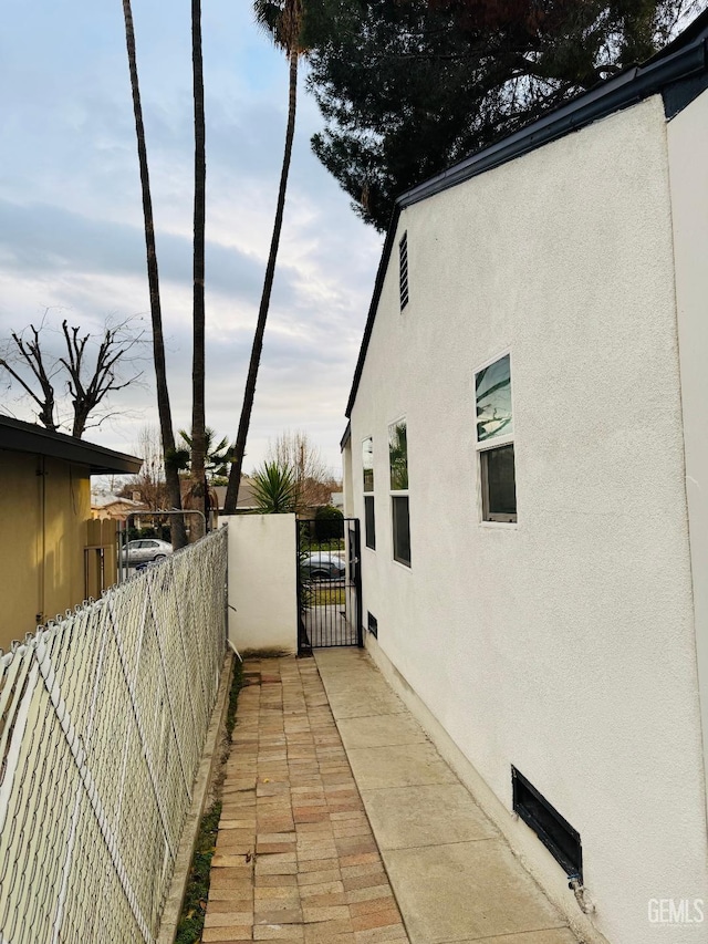 view of home's exterior featuring a gate, fence, and stucco siding