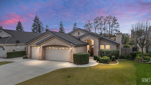 view of front facade featuring a tile roof, a yard, stucco siding, a garage, and driveway