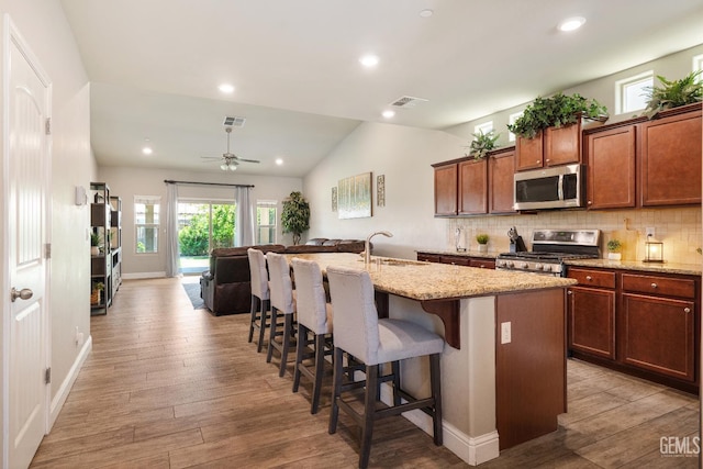 6207 Provincetown Ave, Bakersfield, CA 93313 - kitchen with stainless steel appliances, light wood-style floors, light stone counters, recessed lighting, and lofted ceiling