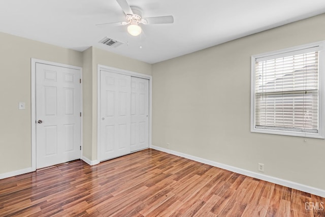 unfurnished bedroom featuring hardwood / wood-style flooring, a closet, and ceiling fan