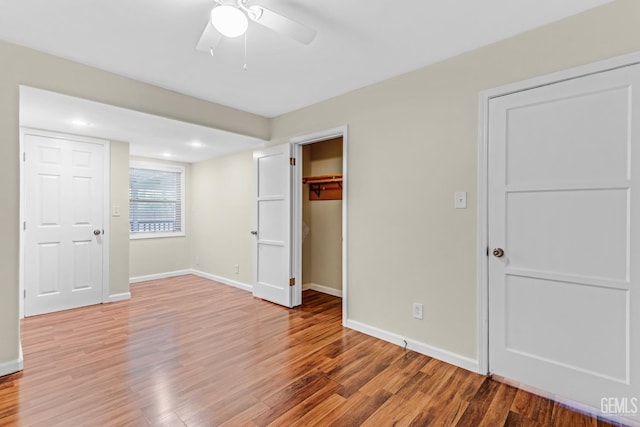 unfurnished bedroom featuring a walk in closet, light hardwood / wood-style floors, a closet, and ceiling fan