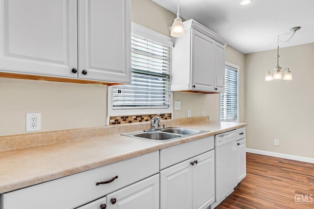 kitchen featuring hanging light fixtures, dishwasher, sink, and white cabinetry