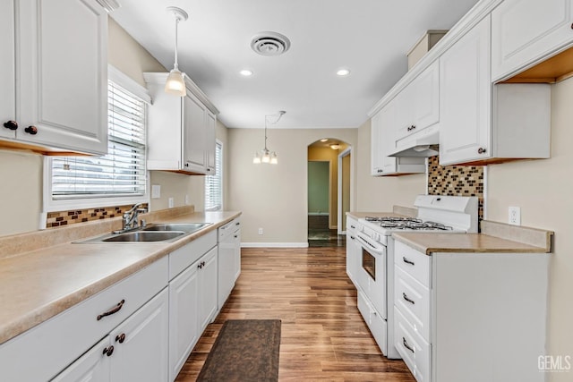 kitchen with sink, white cabinets, hanging light fixtures, white appliances, and light hardwood / wood-style flooring