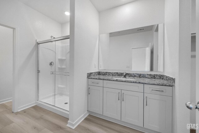 full bathroom featuring visible vents, a stall shower, baseboards, wood finished floors, and vanity