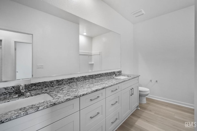 full bath with baseboards, wood finished floors, toilet, and a sink