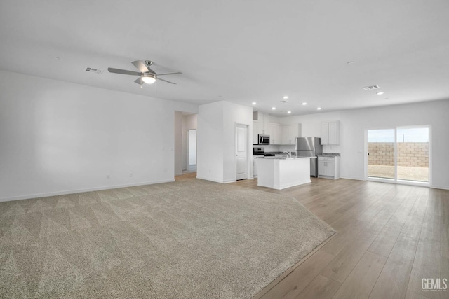 unfurnished living room featuring recessed lighting, light wood-style flooring, baseboards, visible vents, and a ceiling fan