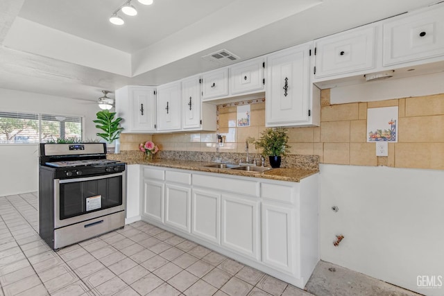 kitchen with stainless steel gas stove, white cabinetry, ceiling fan, and sink