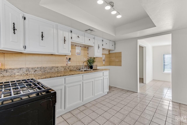 kitchen with light stone countertops, sink, light tile patterned floors, a tray ceiling, and white cabinets