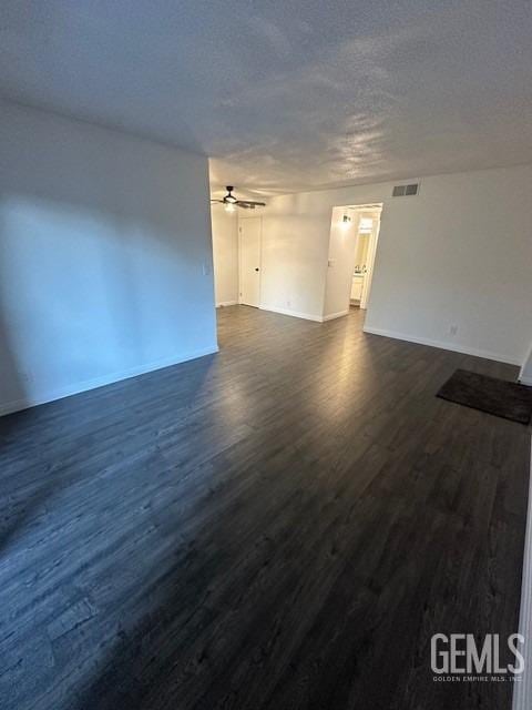 empty room with ceiling fan, dark wood-type flooring, and a textured ceiling