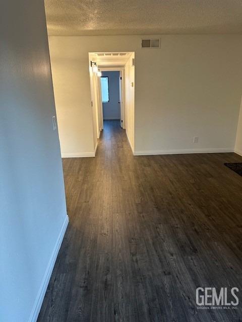 empty room featuring a textured ceiling and dark hardwood / wood-style floors