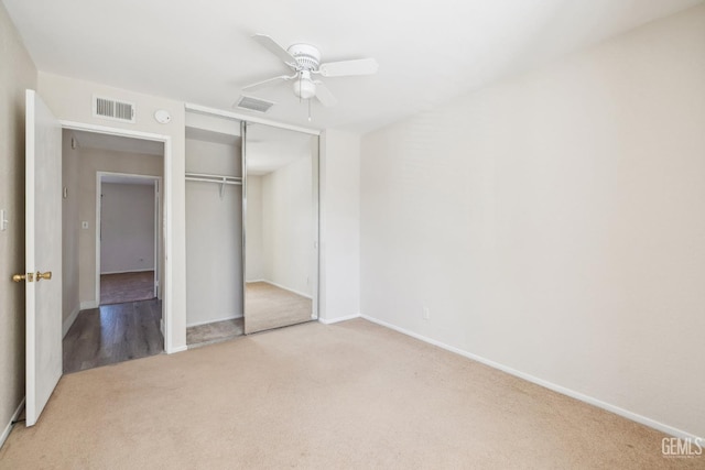 unfurnished bedroom with ceiling fan, light carpet, and a closet