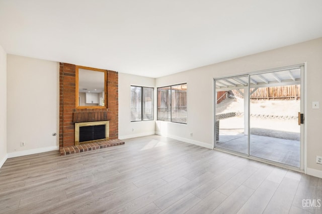 unfurnished living room featuring light wood-type flooring and a brick fireplace