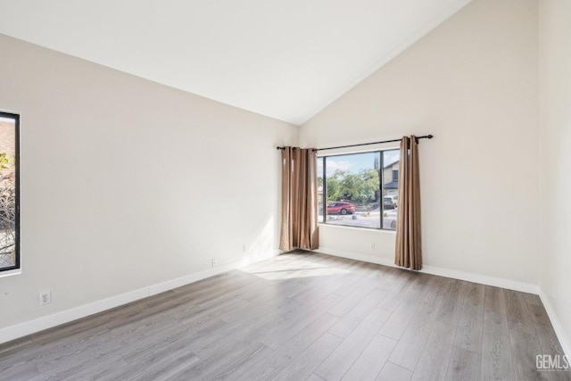 empty room with light hardwood / wood-style floors and high vaulted ceiling