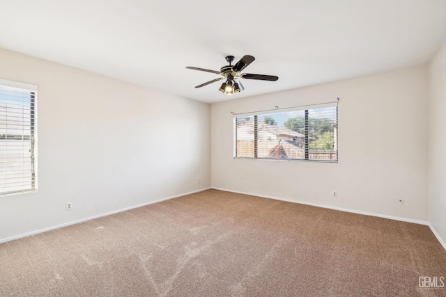 carpeted spare room featuring a wealth of natural light and ceiling fan