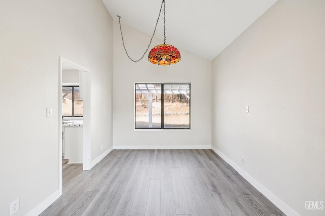 unfurnished dining area with light hardwood / wood-style flooring, high vaulted ceiling, and a chandelier