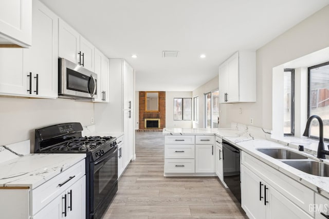 kitchen featuring black appliances, kitchen peninsula, sink, light wood-type flooring, and white cabinetry