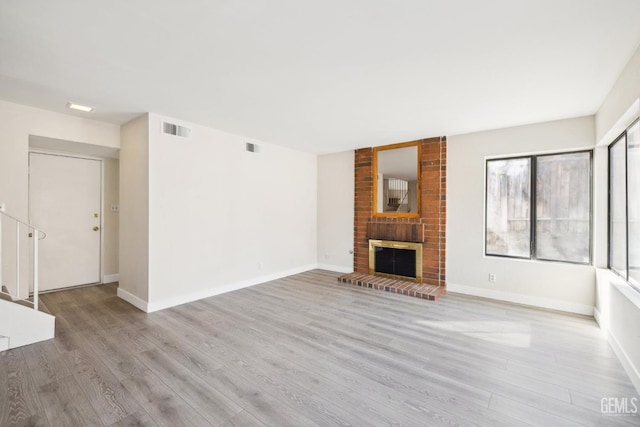 unfurnished living room with a fireplace, light wood-type flooring, and a healthy amount of sunlight