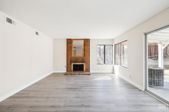 unfurnished living room with light wood-type flooring and a brick fireplace