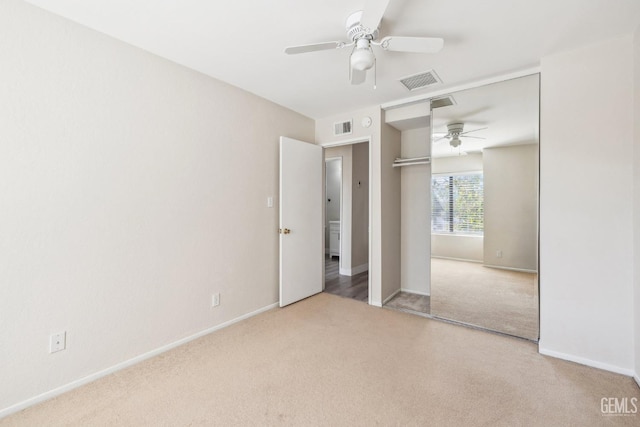 unfurnished bedroom featuring ceiling fan, light colored carpet, and a closet