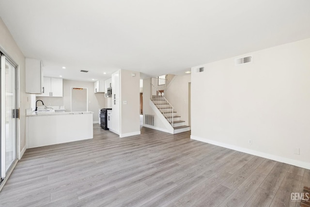 unfurnished living room with sink and light hardwood / wood-style flooring