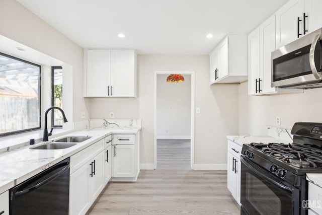 kitchen with sink, light stone counters, white cabinetry, and black appliances