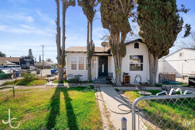 view of front facade with a front lawn, fence, and stucco siding