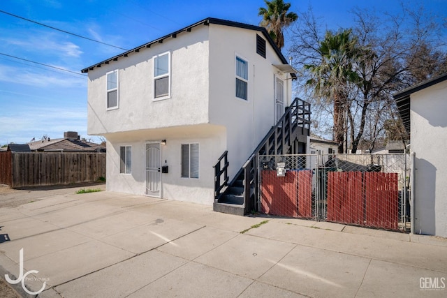 view of front of property with a patio area, fence, and stucco siding