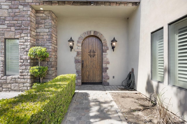 view of exterior entry featuring stucco siding and stone siding