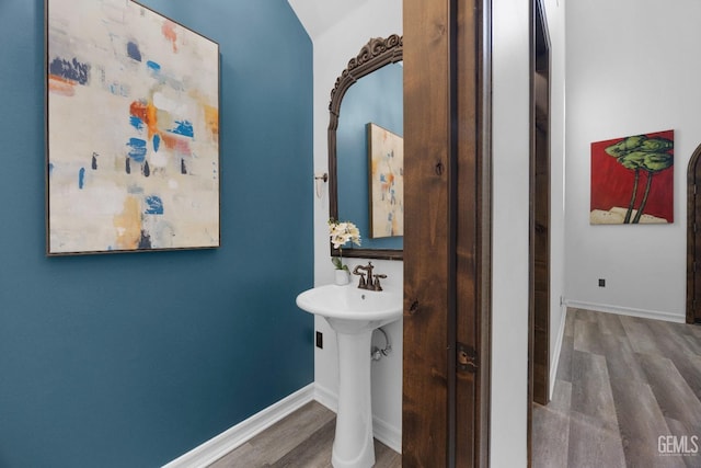 bathroom with baseboards, wood finished floors, and a sink