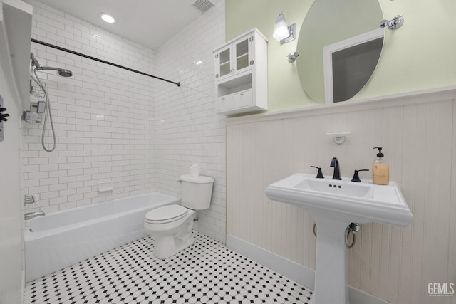 full bath featuring a wainscoted wall, toilet, bathtub / shower combination, and visible vents