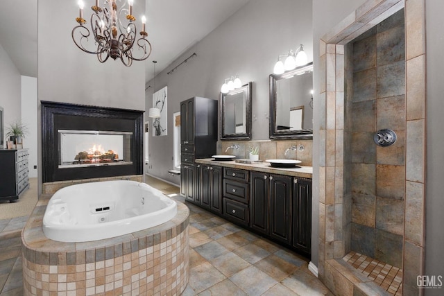 bathroom featuring a chandelier, double vanity, a tub with jets, tiled shower, and tasteful backsplash