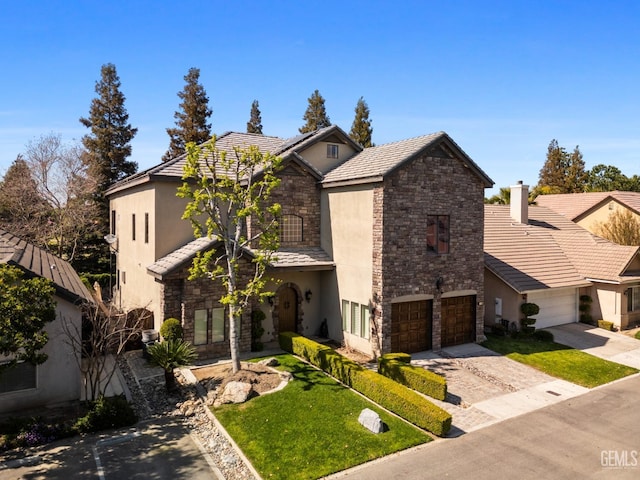 view of front facade with driveway, a front yard, stone siding, stucco siding, and a tiled roof