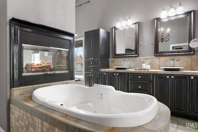 full bath with double vanity, a sink, a whirlpool tub, and tasteful backsplash