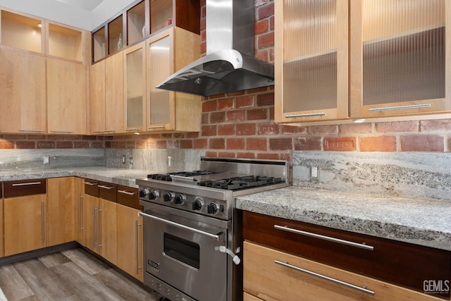 kitchen with decorative backsplash, premium range, light stone countertops, dark wood-type flooring, and wall chimney range hood