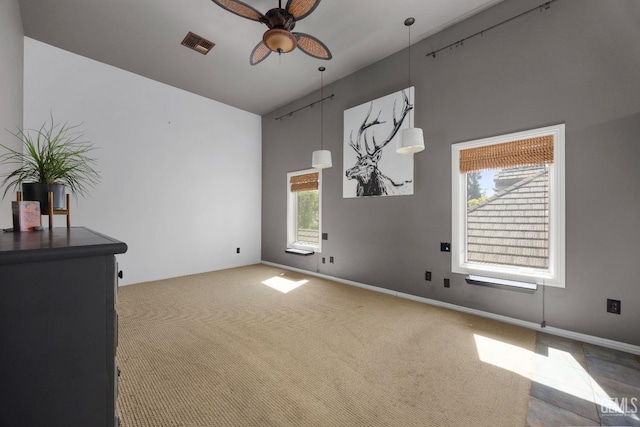 interior space with visible vents, baseboards, a ceiling fan, carpet floors, and a high ceiling