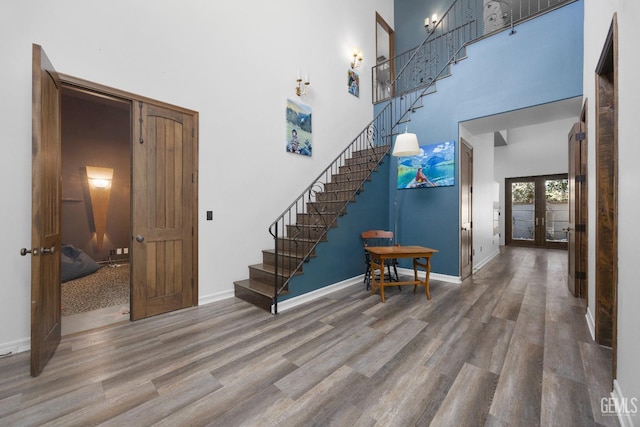 staircase featuring a high ceiling, wood finished floors, and french doors