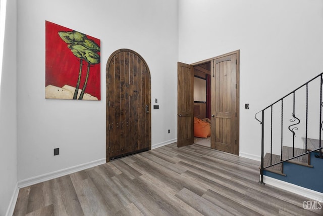 entryway with baseboards, a towering ceiling, wood finished floors, and stairway