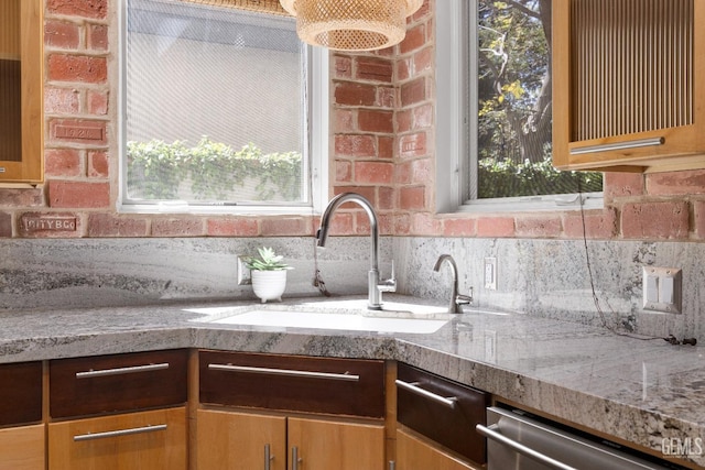 kitchen with dishwasher, a sink, brick wall, and a healthy amount of sunlight