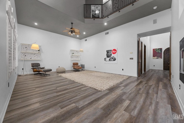 game room featuring baseboards, ceiling fan, a high ceiling, and wood finished floors