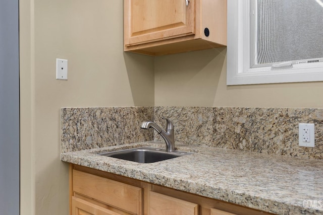 kitchen featuring backsplash, a sink, light brown cabinets, and light stone counters