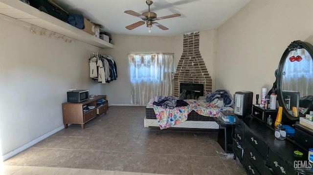 bedroom with dark tile patterned floors, ceiling fan, and a fireplace