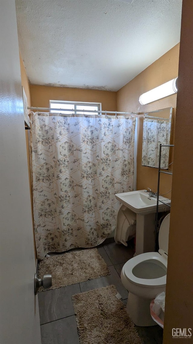 bathroom featuring tile patterned flooring, toilet, a textured ceiling, and walk in shower