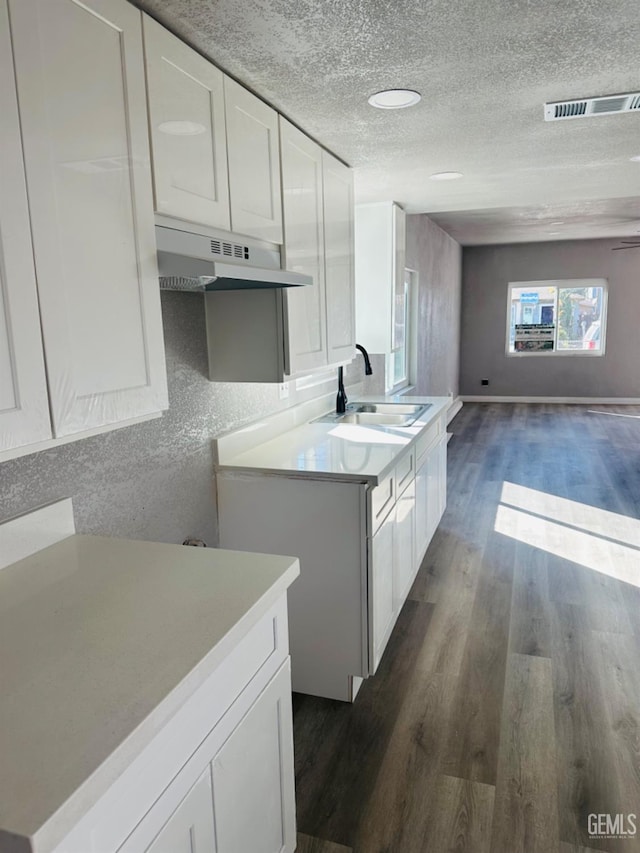 kitchen featuring a textured ceiling, sink, white cabinets, and dark hardwood / wood-style floors