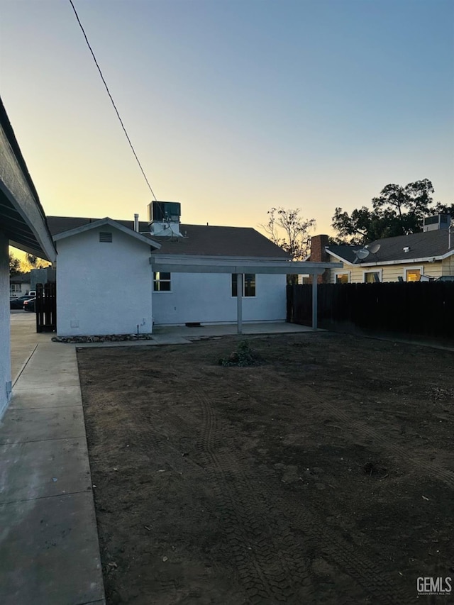 back house at dusk featuring a patio area and central AC