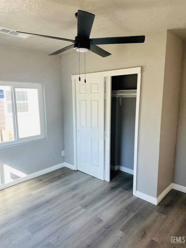 unfurnished bedroom featuring hardwood / wood-style floors, ceiling fan, a textured ceiling, and a closet