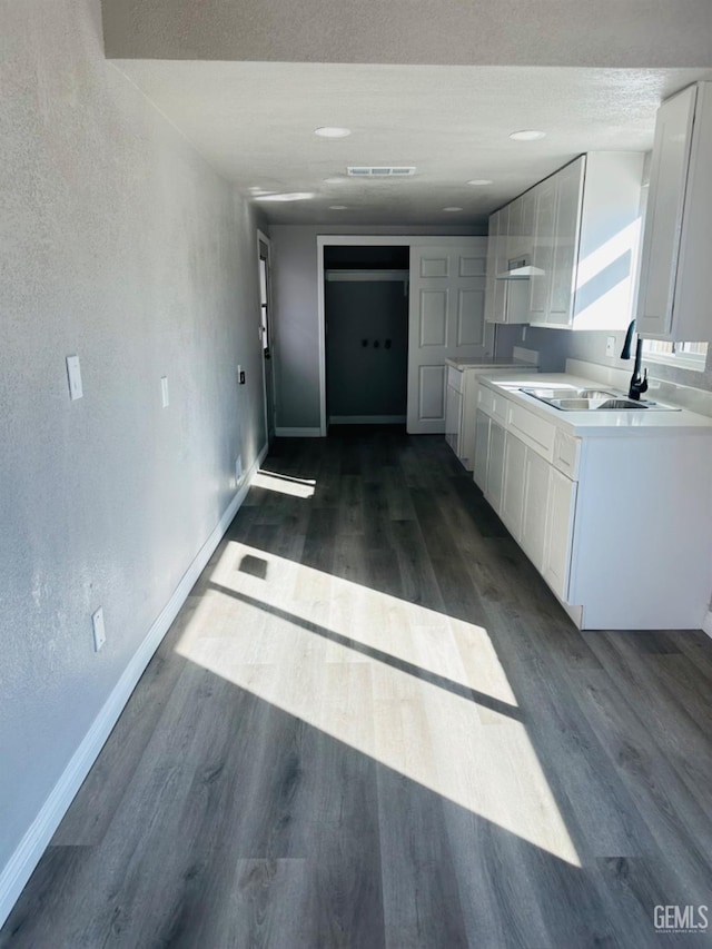 kitchen featuring a textured ceiling, dark hardwood / wood-style floors, white cabinetry, and sink