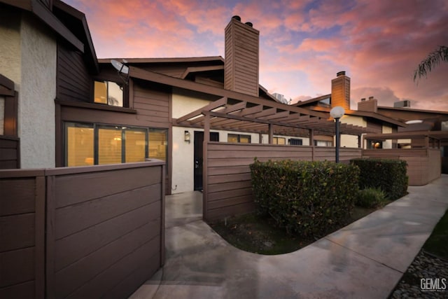 property exterior at dusk featuring a pergola