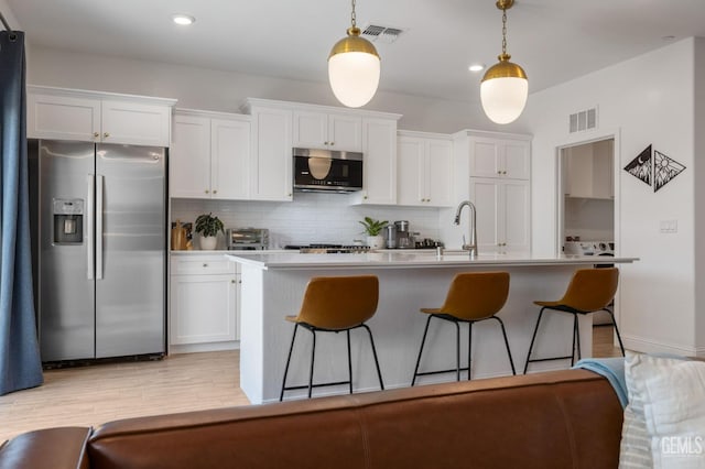 kitchen featuring stainless steel appliances, a sink, white cabinets, backsplash, and recessed lighting