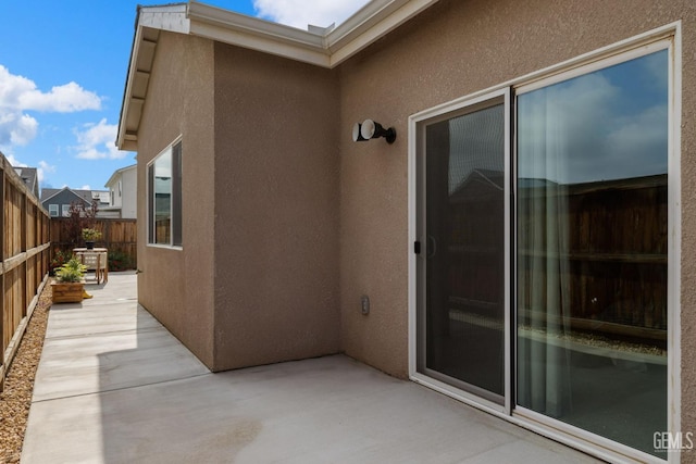 entrance to property featuring a patio, fence, and stucco siding
