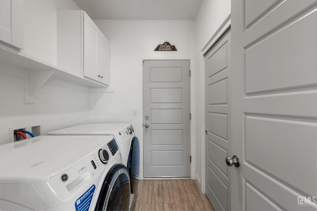 clothes washing area featuring washing machine and dryer, cabinet space, and light wood finished floors